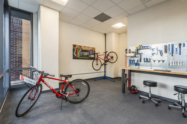 Bike repair room with bike stands and tools on rack.