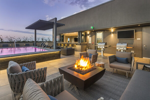 Rooftop lounge with plush seating, fire pit, pool with pergola, and built in BBQ grills.