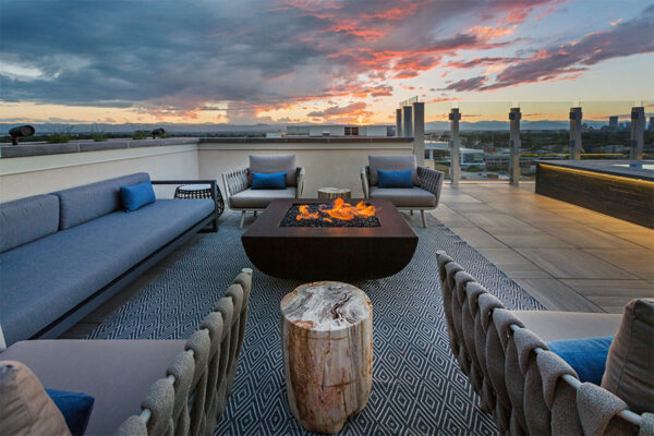 Rooftop patio with comfortable seating and fire pit overlooking Denver skyline.