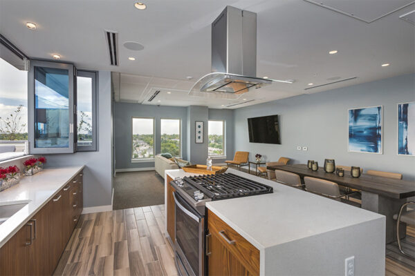 Demo kitchen with wood floor and cabinets, light counters, and stainless steel appliances.