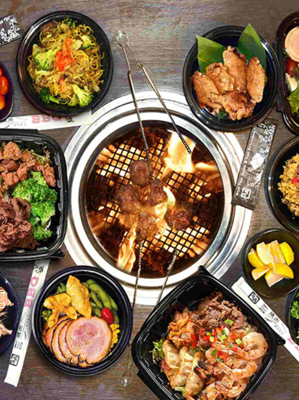 Several platters of food around a fire pit.